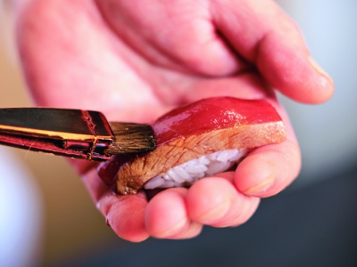 After deftly preparing the rice, he brushes soy sauce on the rice to make it easier to eat for guests at the counter.