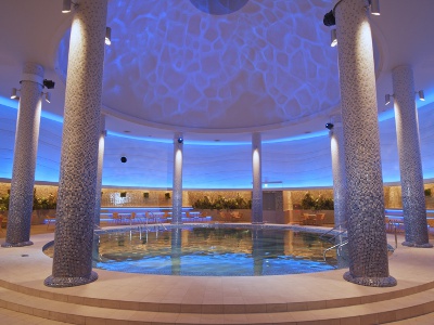 A circular indoor hot spring pool decorated in soothing colors. The flowing warm water is comfortable.